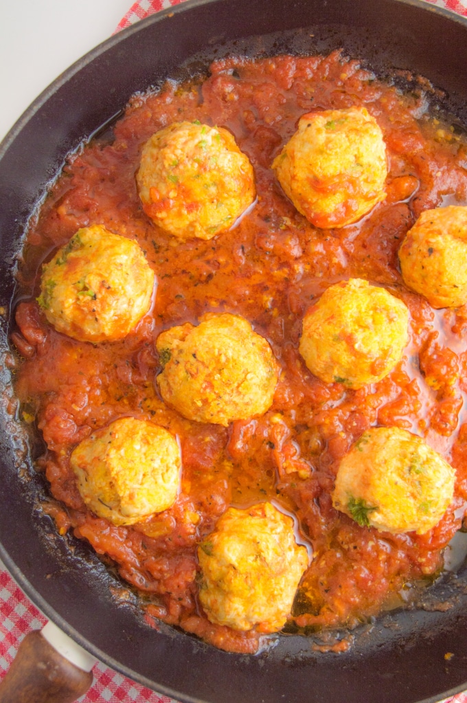 A cast iron skilled filled with nine turkey meatballs cooked in tomato sauce