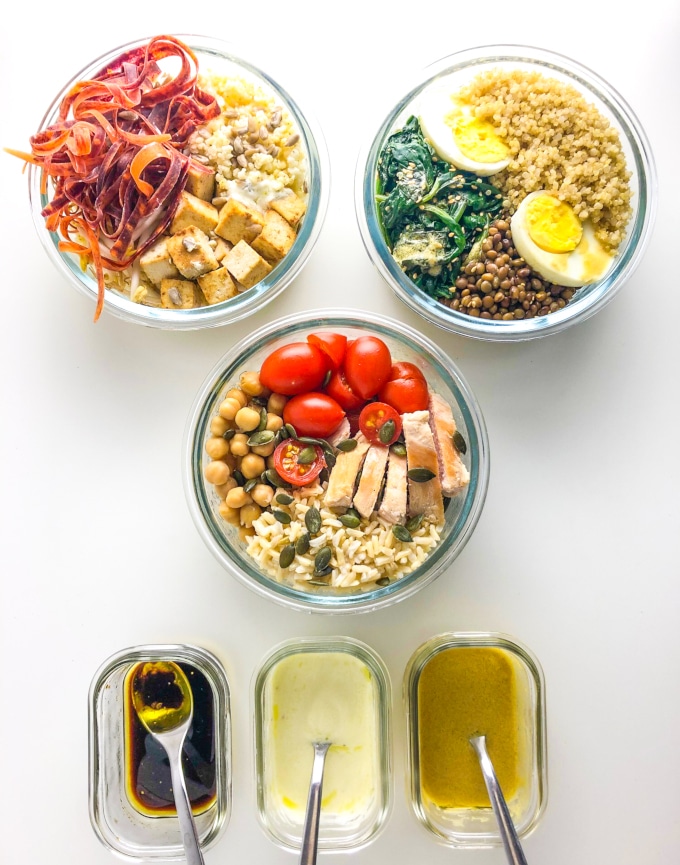 three packed nourish bowls with three dressings in a rectangular container