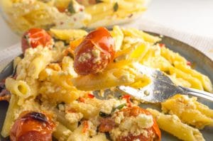 a fork with baked feta pasta and a cherry tomato