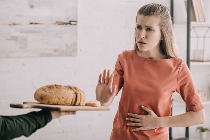 Mulher recusa uma bandeja de pão com a mão e com a outra mão na barriga